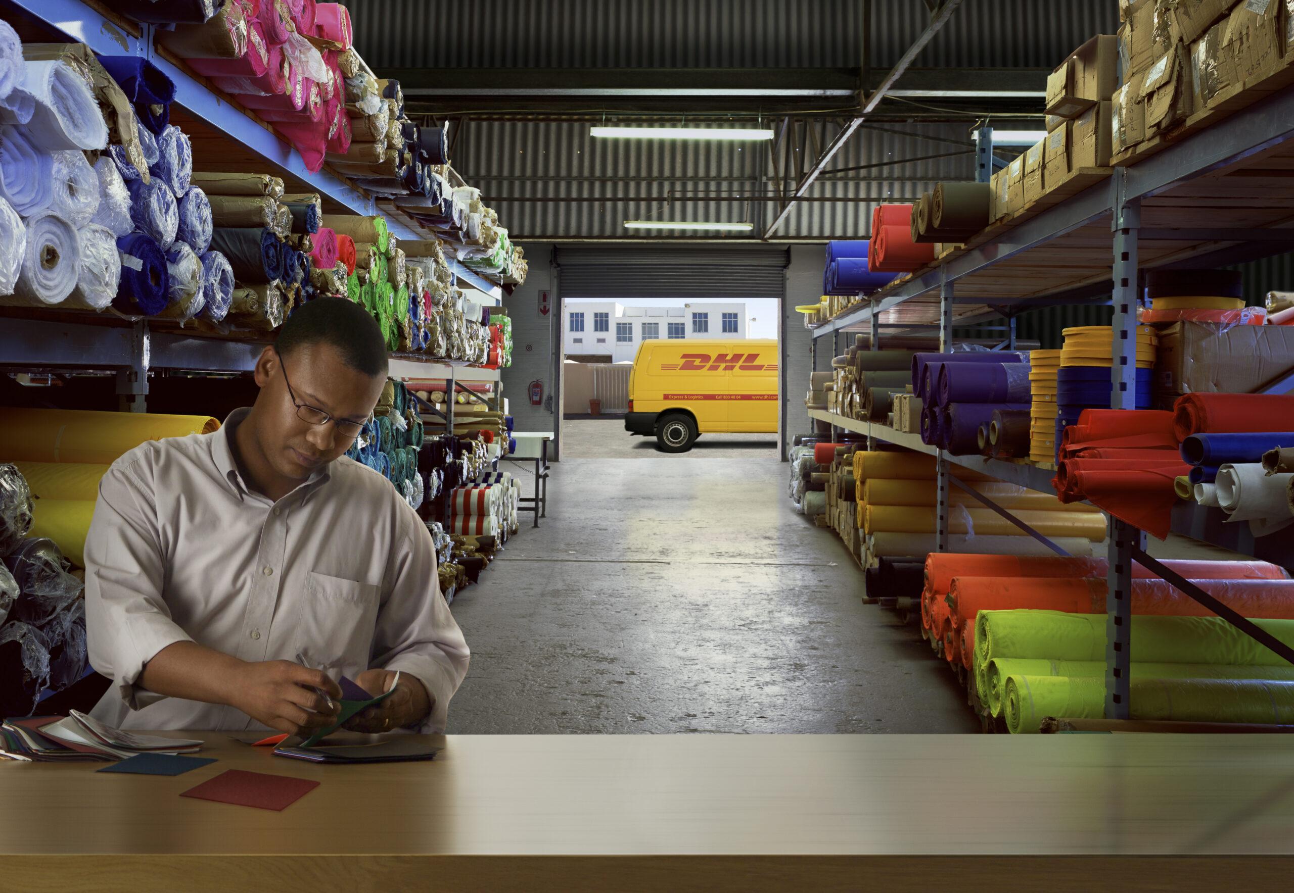 Man in warehouse with DHL van in background outside