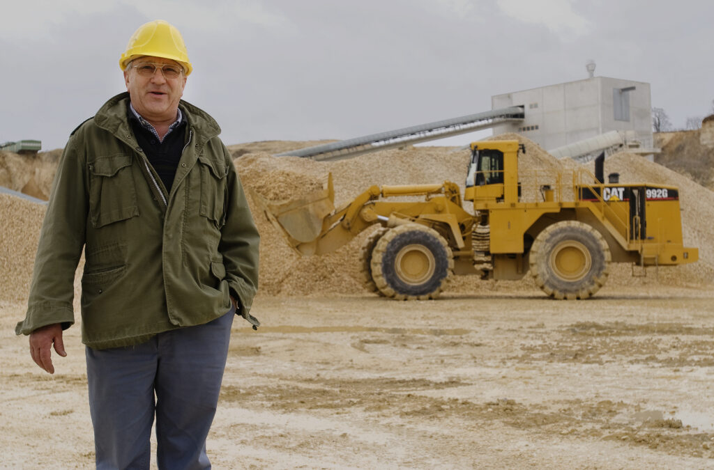 Man in Hard Hat in front of Caterpillar machine in Quarry