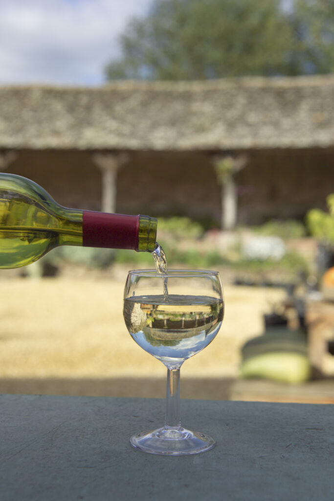 wine poured into glass with farm buildings in background