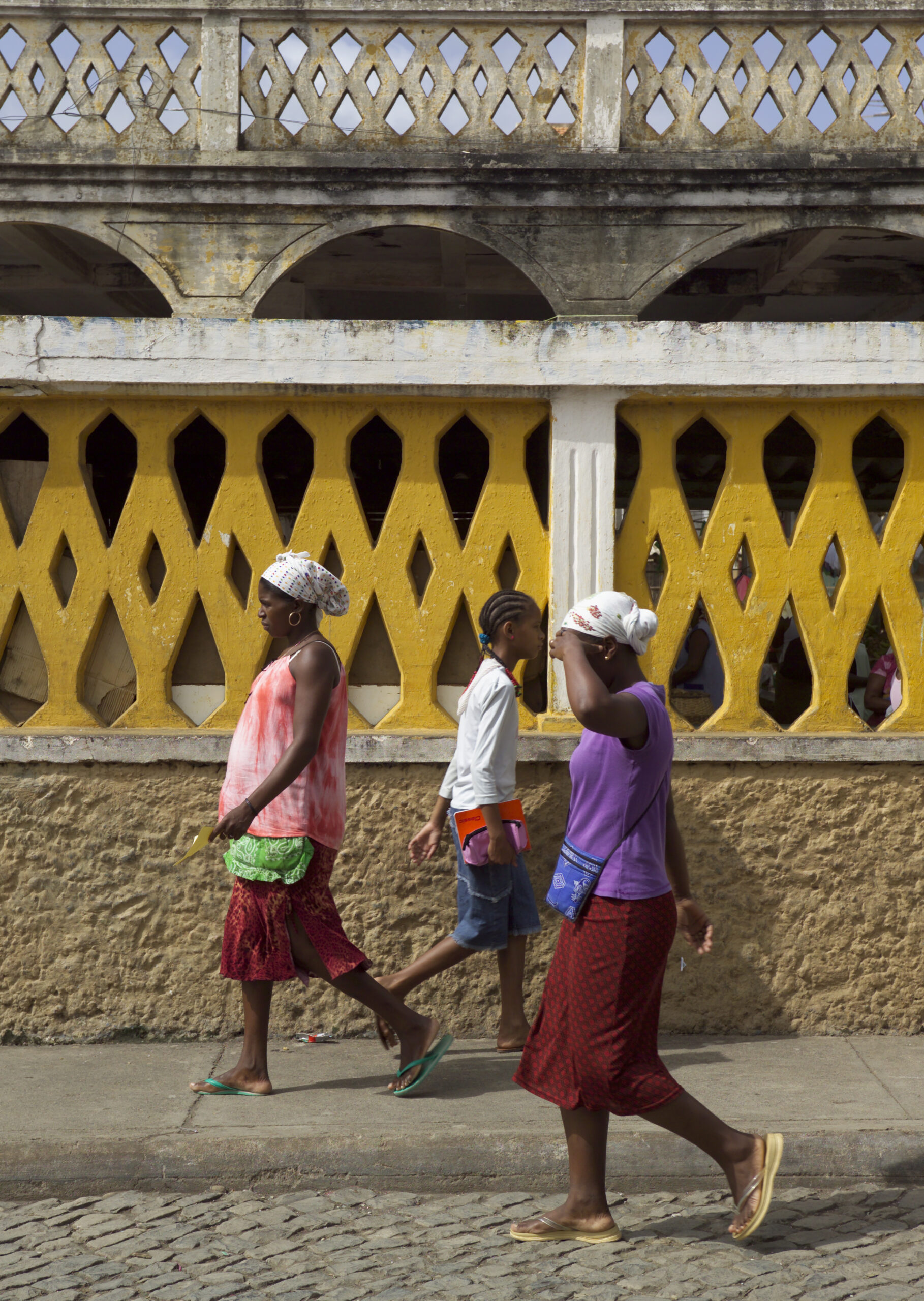 Three Ladies seen fom side walking with patterned concrete background