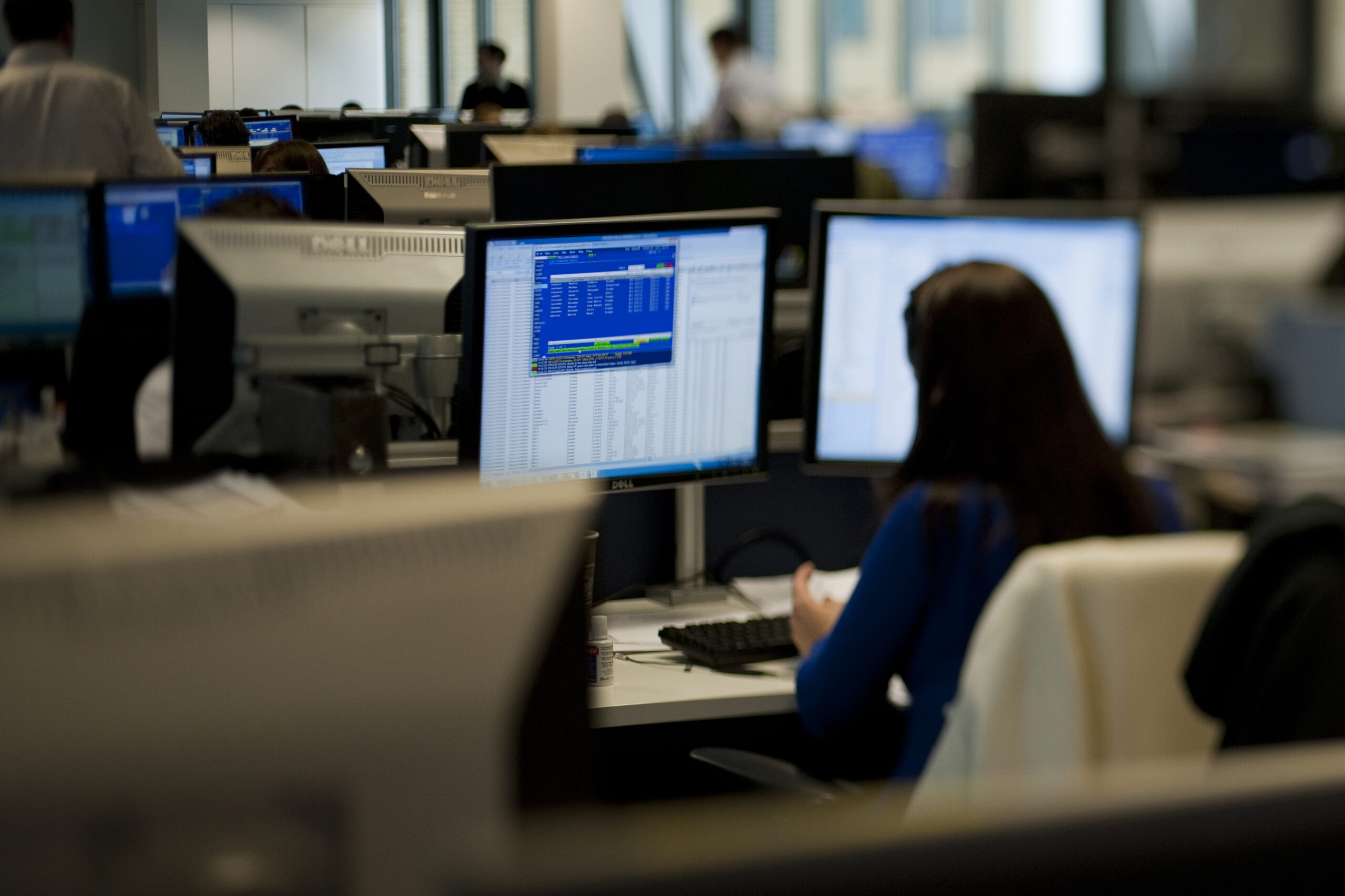 trading area with banks of computers and lady in silhouette