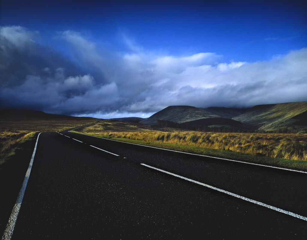 road in upland Wales with clouds across mountains in background,