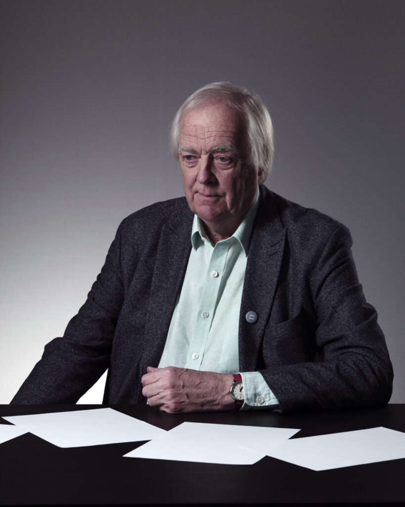 Sir Tim Rice, at table with blank pages around him. Photograph by Lorentz Gullachsen.