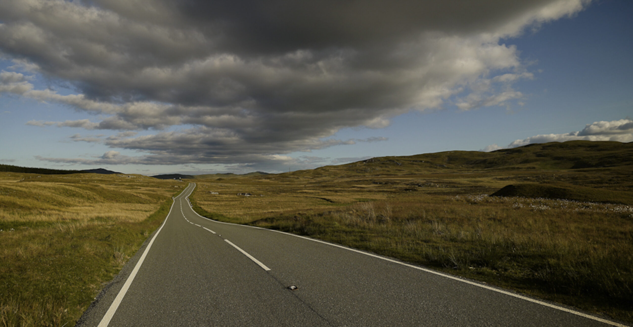 long empty road in wales with clouds