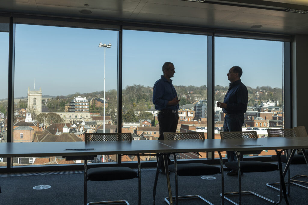 two me in sillouette in meeting room, with town skyline