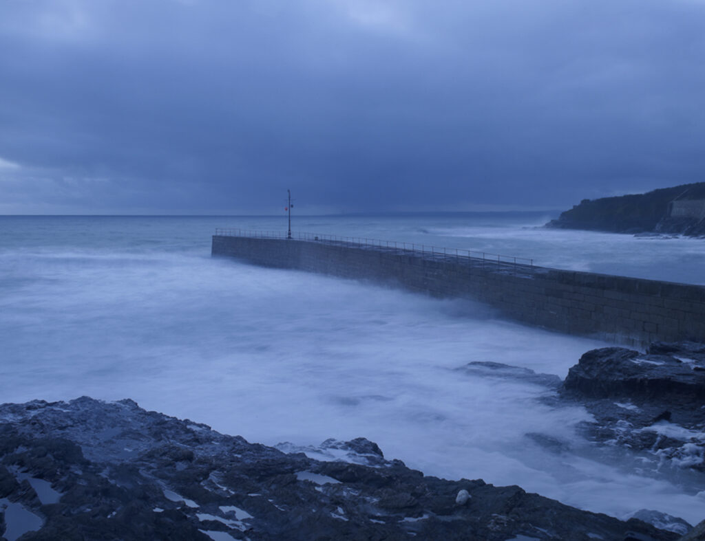 Stormy sea with Harbour Wall at Porthleven, blue cast