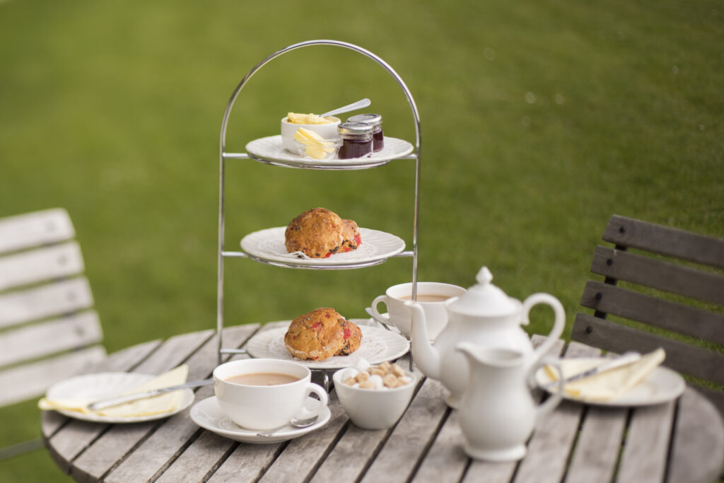 cake stand with scones, cream, jam and tea pot and cups