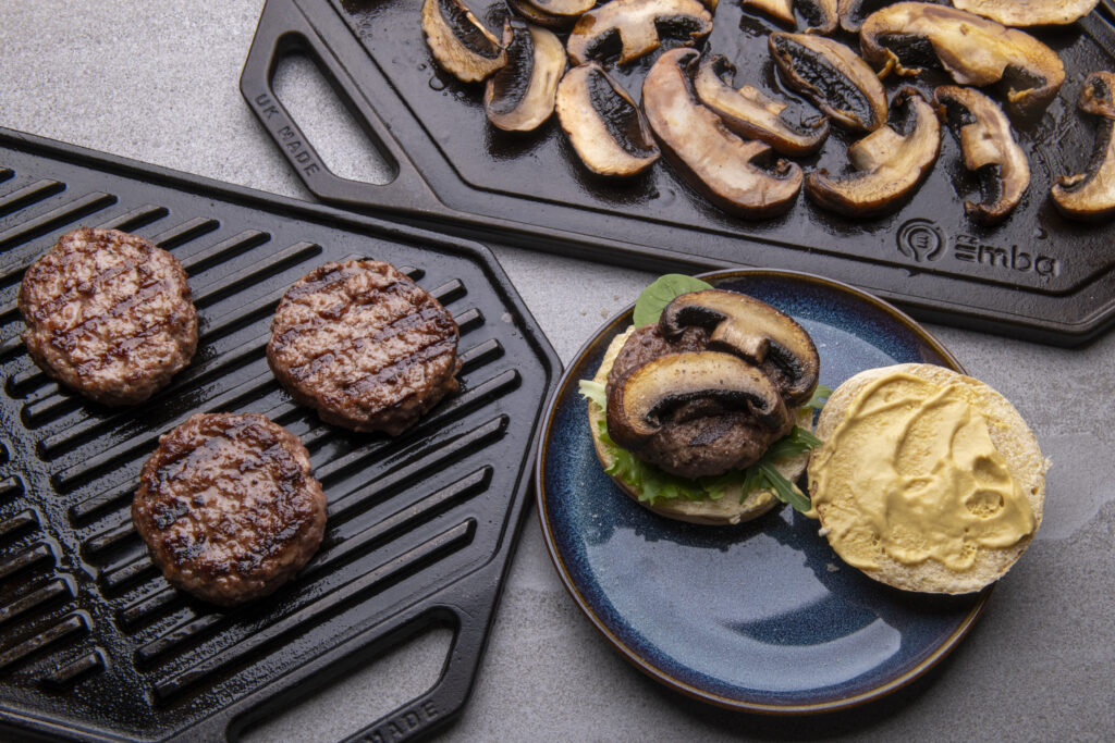 Burgers and mushrooms on cast iron griddles with Bap and sauce