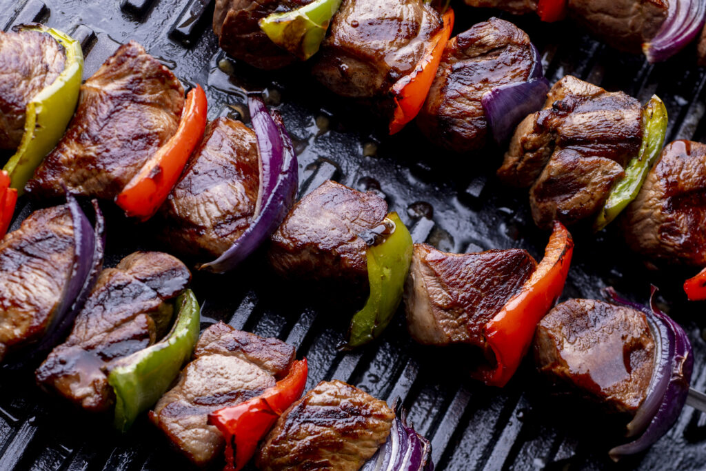 Close up of lamb kebabs with peppers on top of cast iron Emba cookware griddle