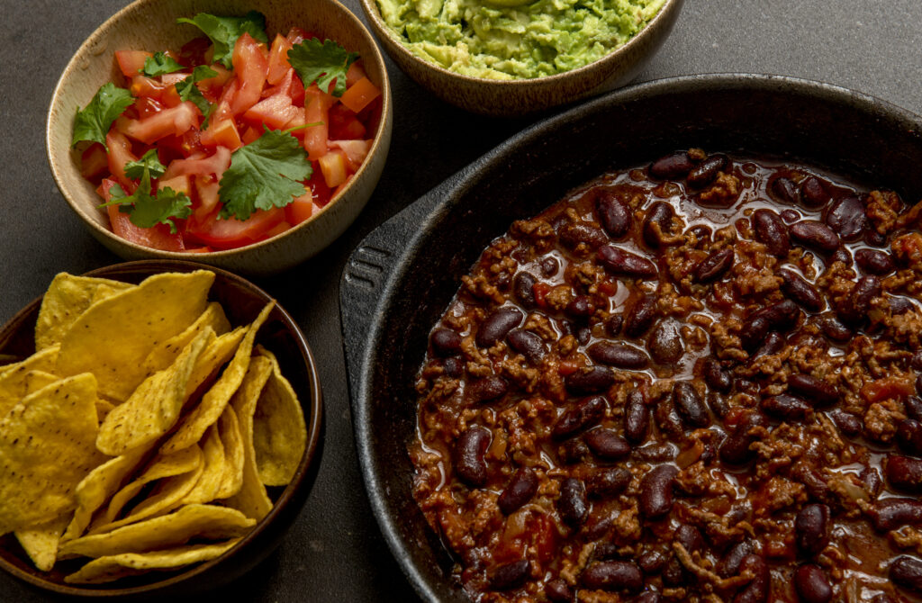 Chilli Con Carne in Cast Iron Skillet with salsa, chips and dip