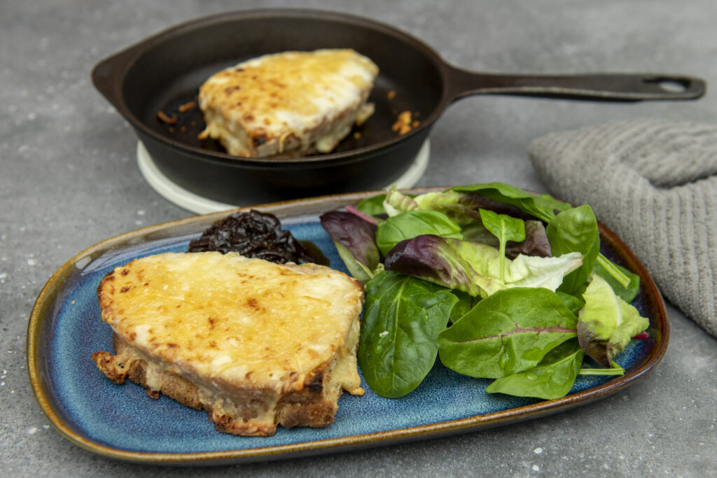 Croque Monsieur on plate with salad, skillet in background