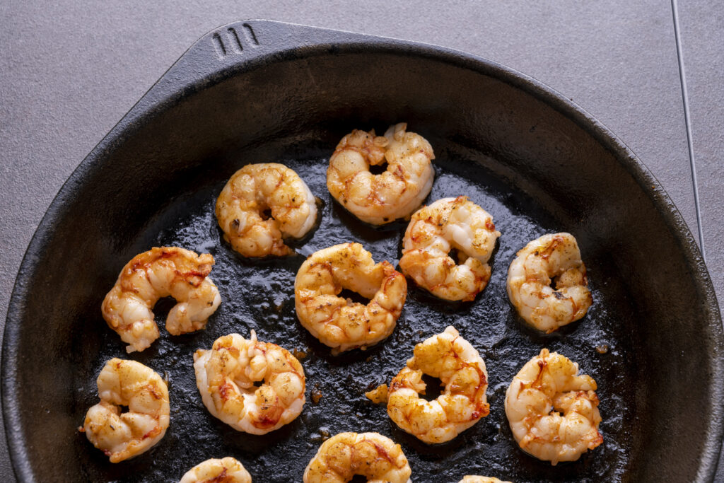 cooked prawns in cast iron skillet with tile cackground