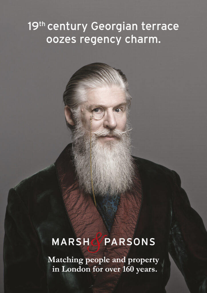 Ad poster with man dressed in smoking jacket, with white beard and monocule