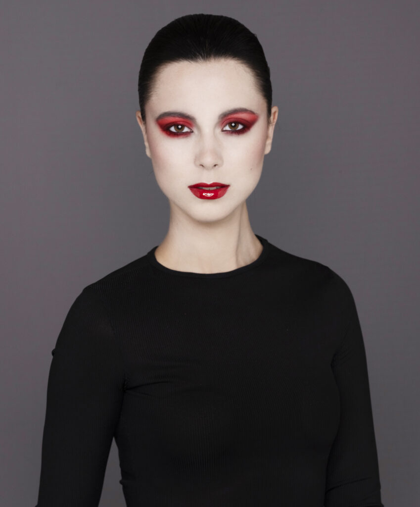 female model with stark make up red lips , white skin and black dress