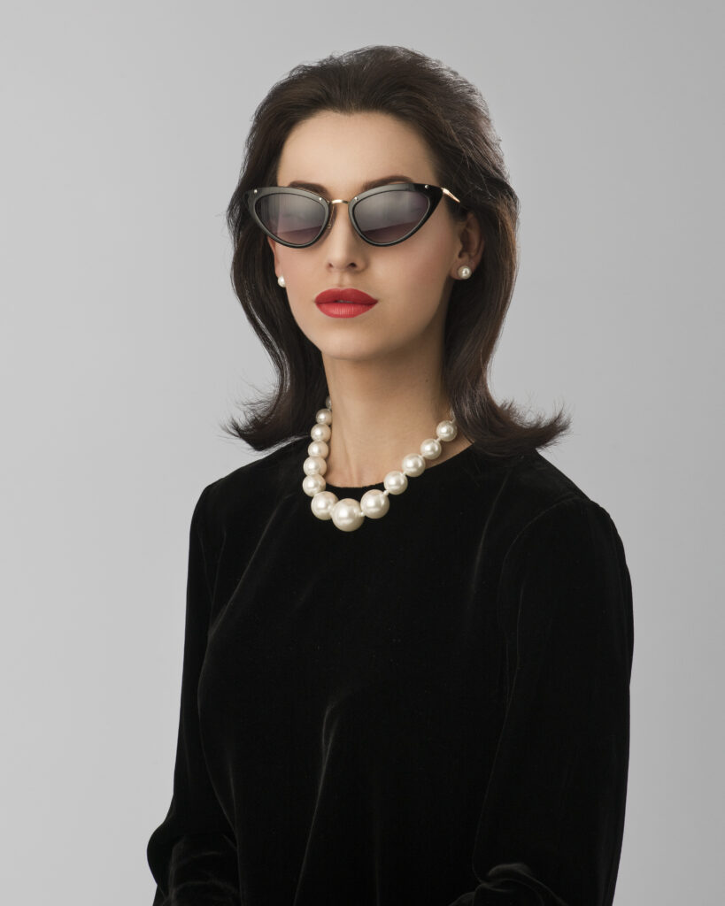 Lady in sunglasses and large necklace looking like Princess Margaret in1960's
