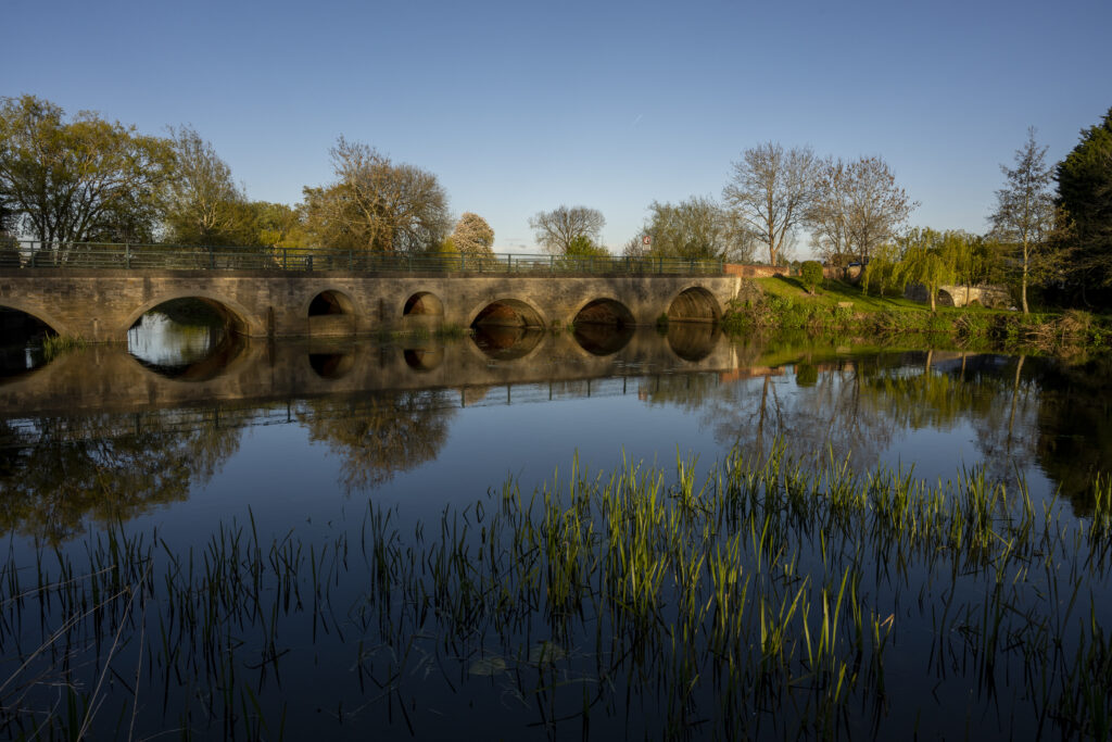 bridge reflecting in Avon with reeds in foreground