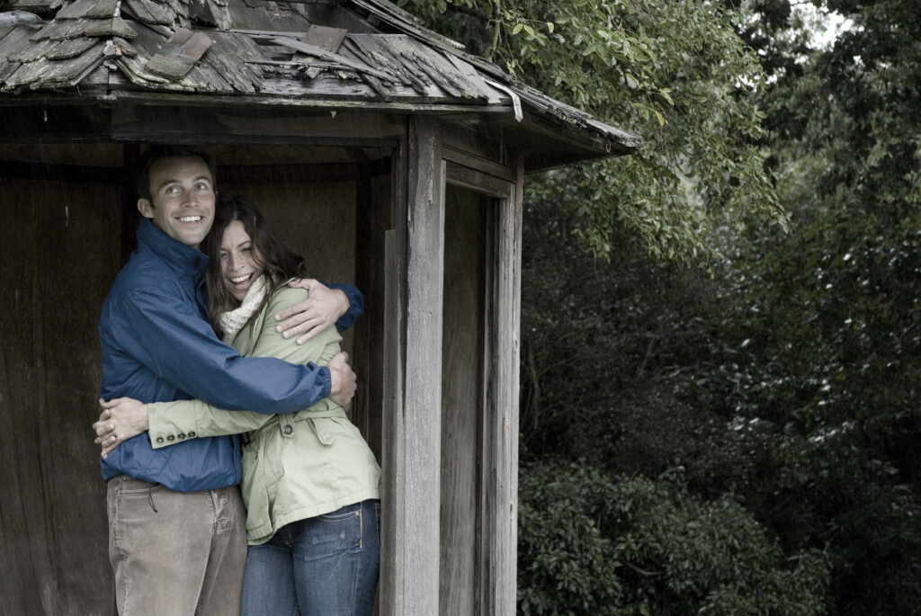happy couple sheltering under shack holding each other