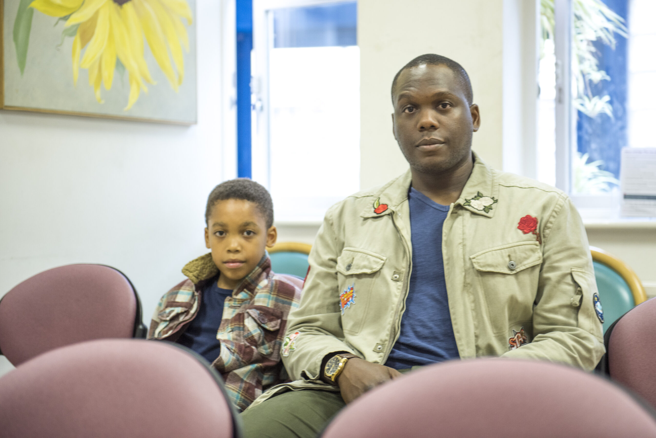 Father and son in waiting room looking concerned