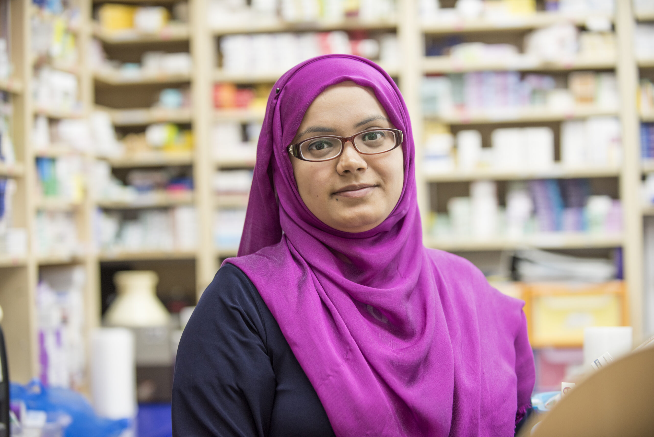 Ladin with headscarf in Chemist looking to camera