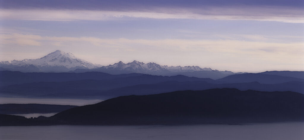 blue tinted landscape with high snow covered mountain