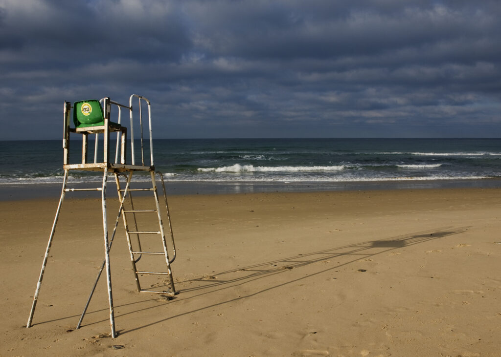 Beach guard chair on deserted beach with stormy sky