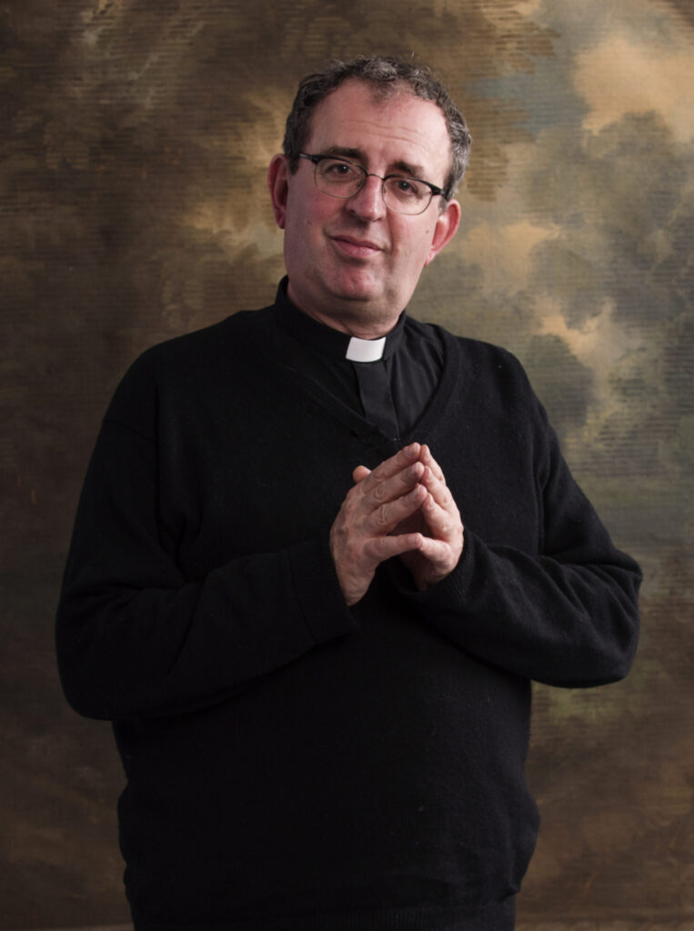 Rev Richard Coles, hands together with painted background