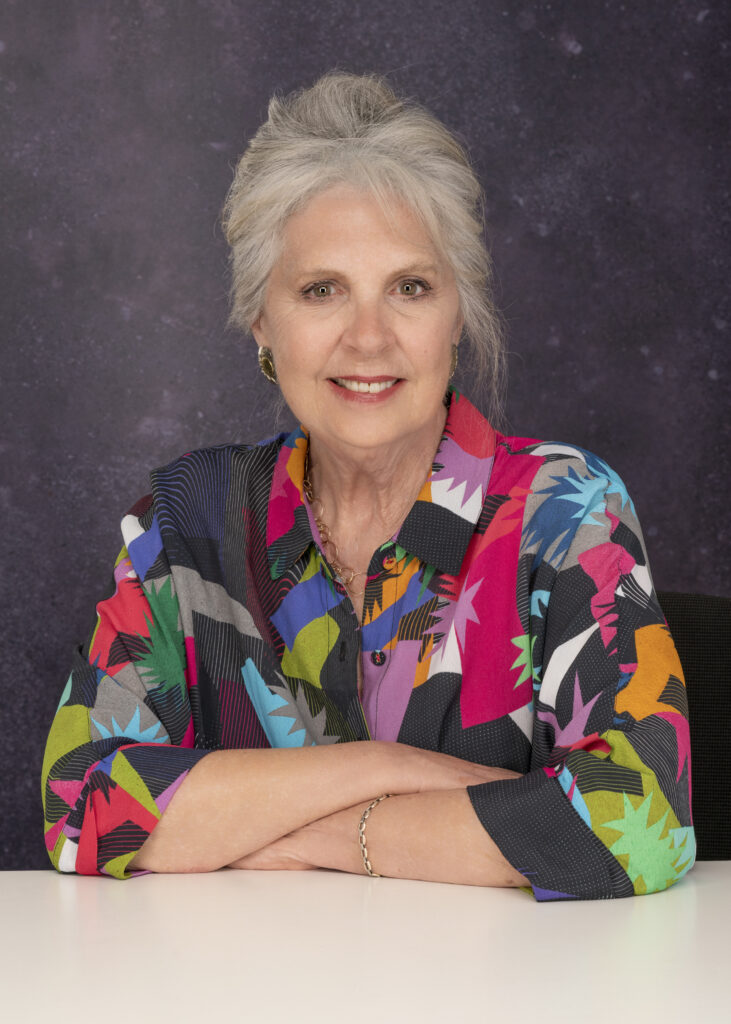 Penelope Wilson in coloured dress smiling to camera