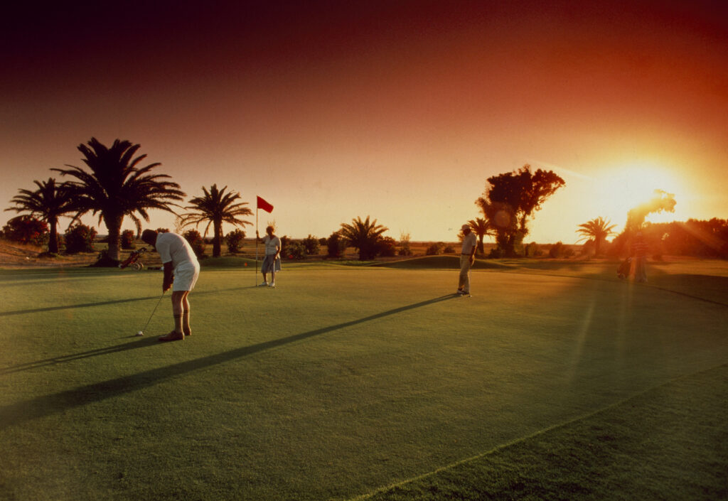 on putting green with sunrise two couples playing golf