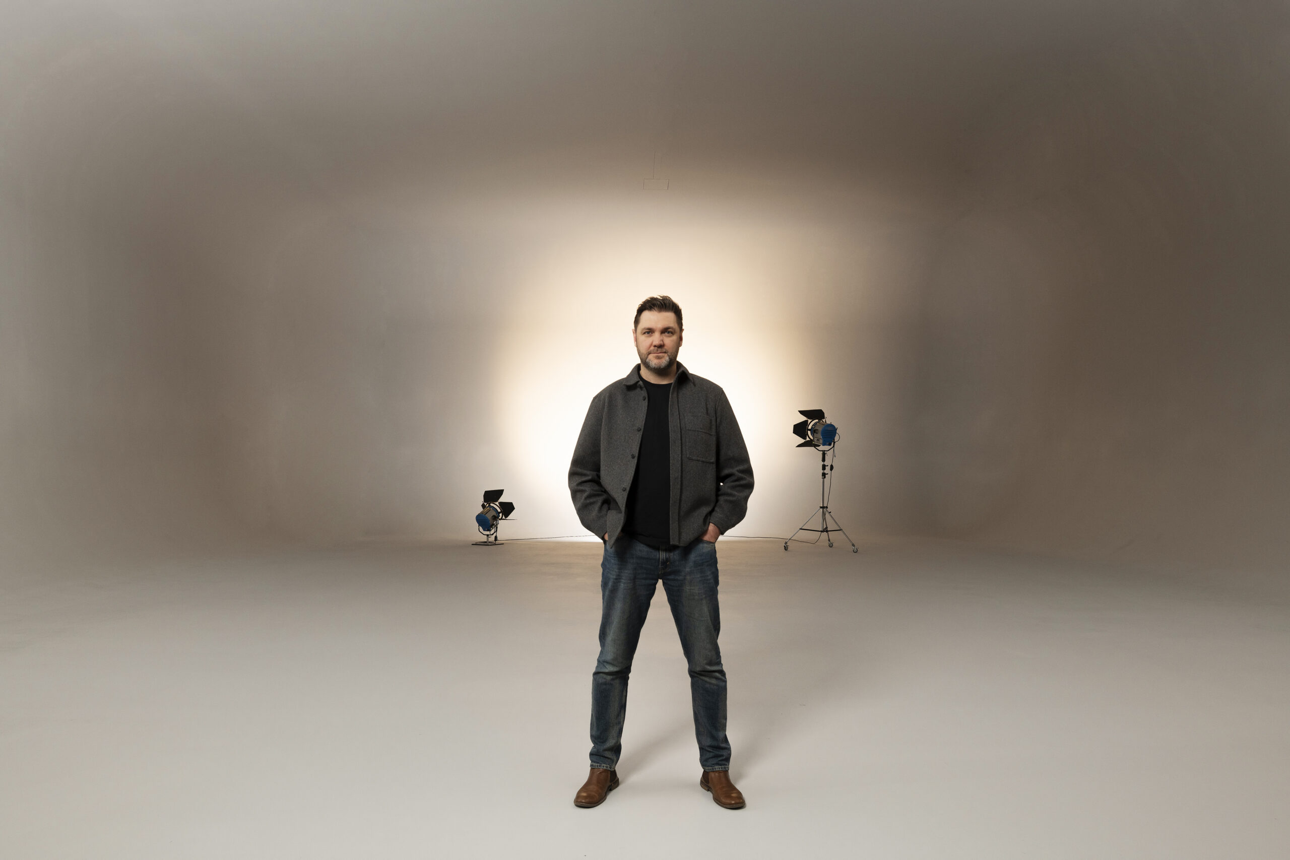 man in very large studio space with professional spot lights in distance