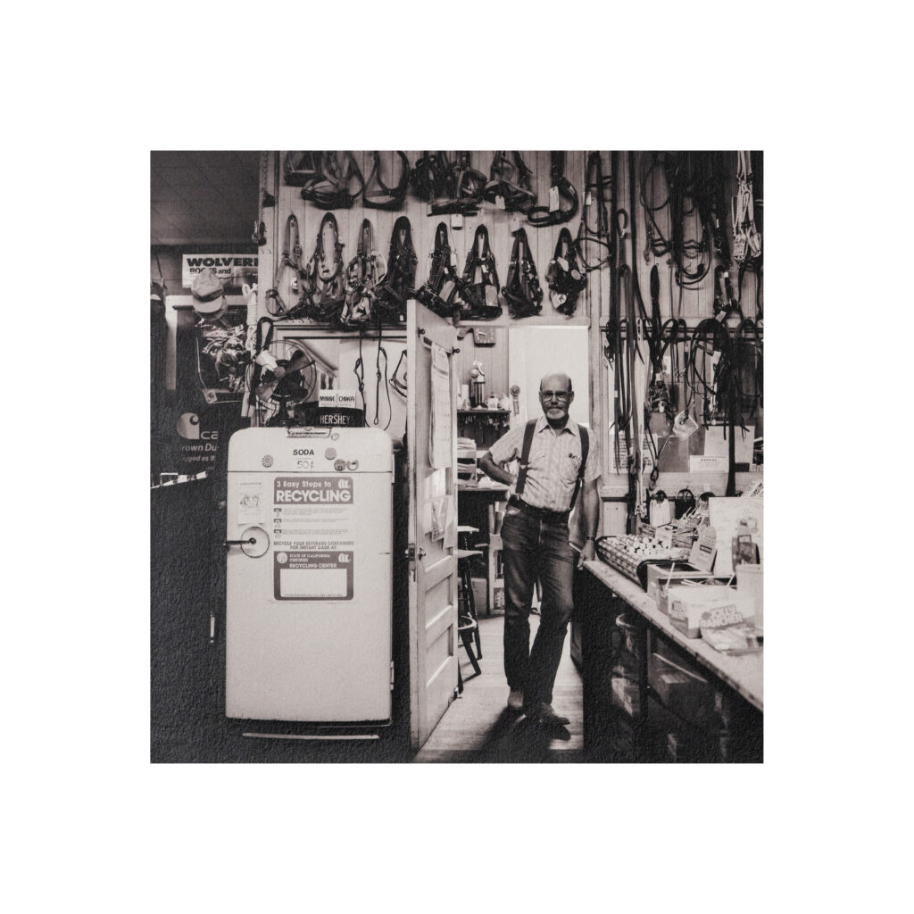 Man with beard in a doorway within a store looking as if it was 19th century, actually 20th Black and white art print