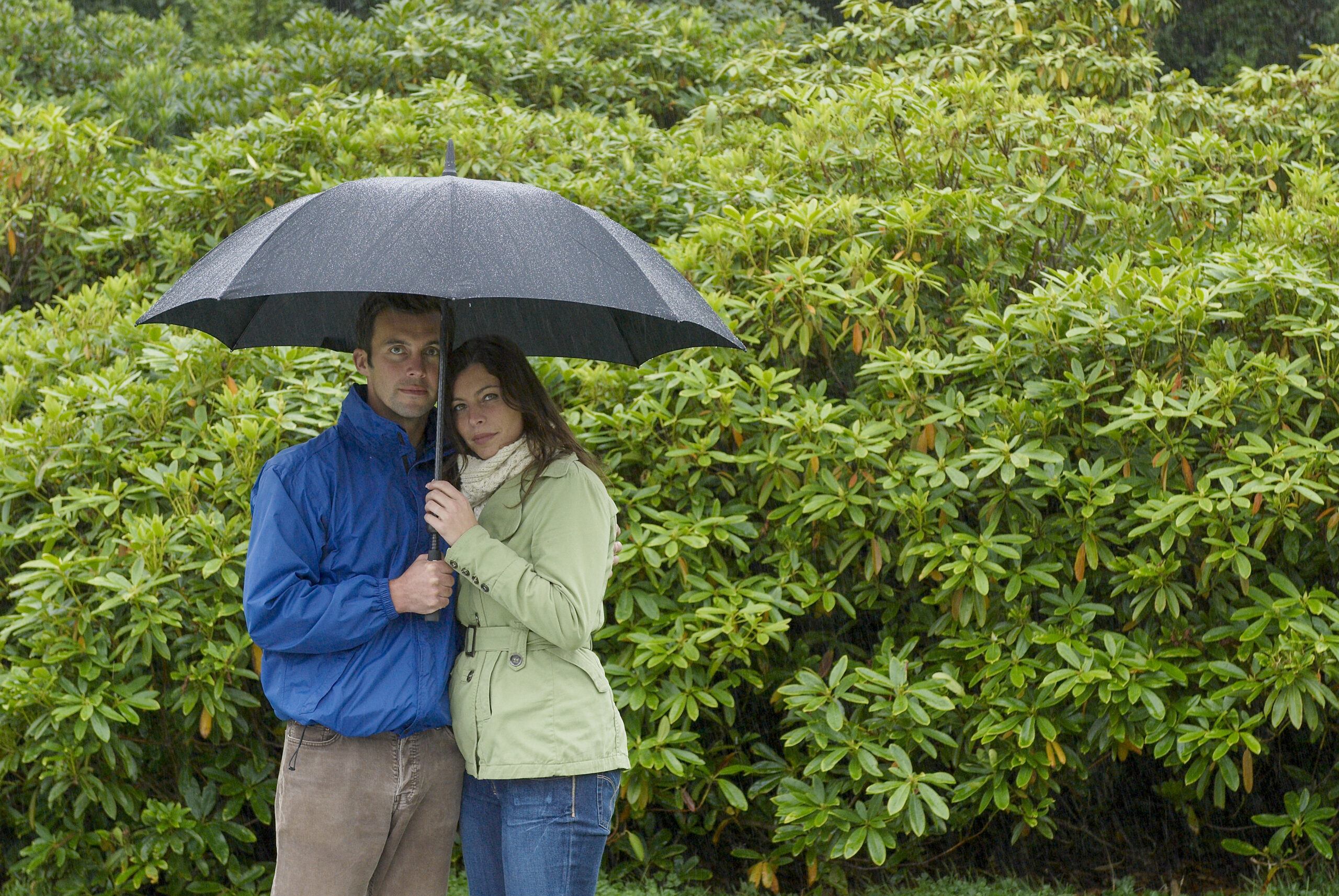 young couple under an umbrella looking concerned